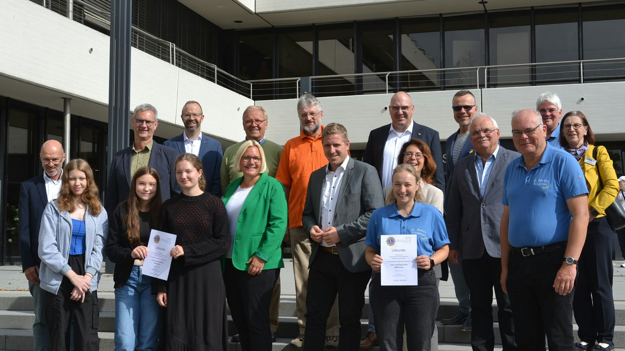 Vor dem Euskirchener Kreishaus stehen Vertreter von sechs Lions Clubs sowie der Mechernicher St.-Barbara-Jugendgruppe und der Schleidener Clara-Fey-Schule mit Landrat Markus Ramers, der ihnen den Jugendpreis der Lions überreicht hat.
