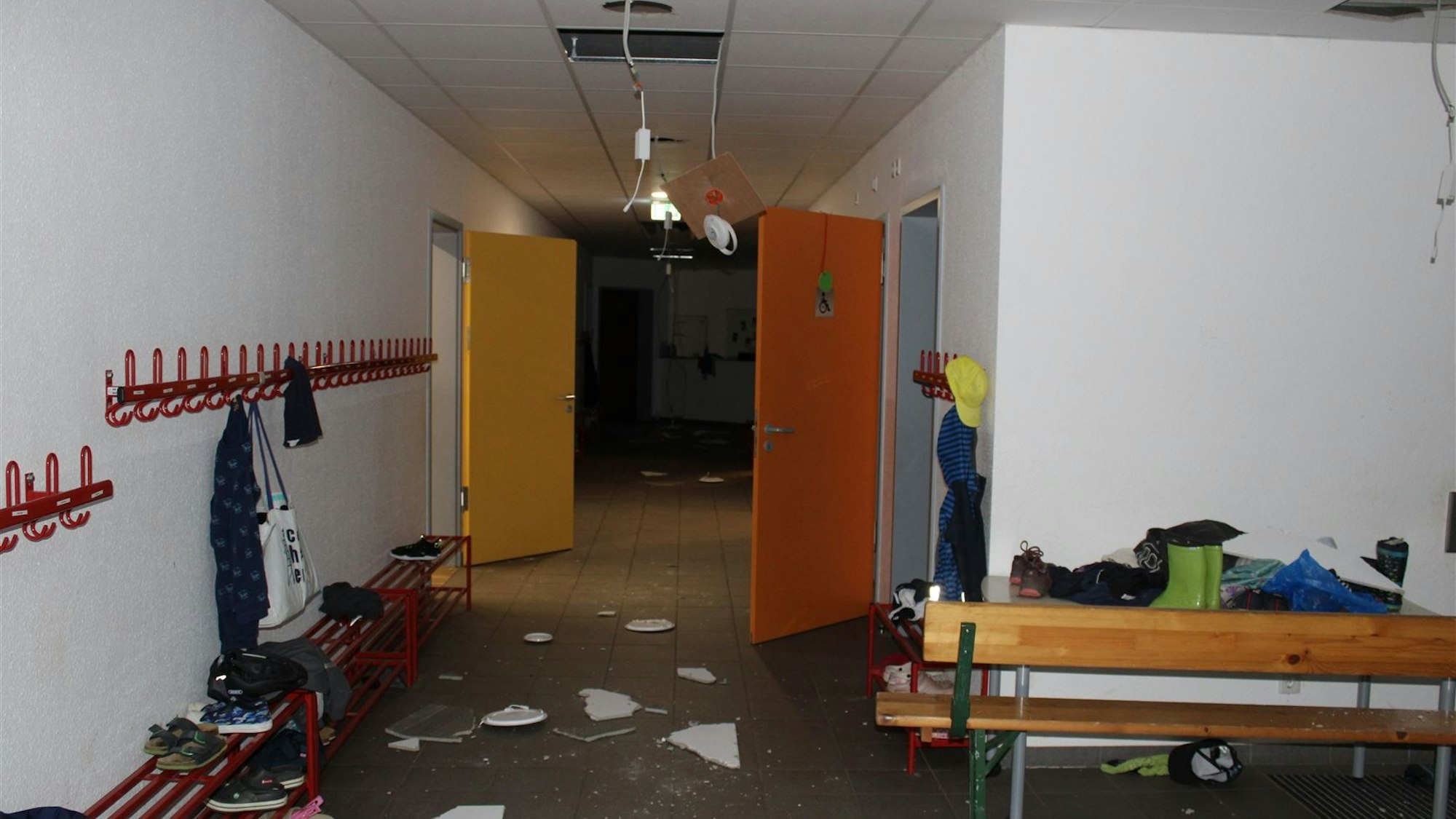 Lampen sind in einem Schulflur aus der Decke gerissen, Dekcenplatten und Türen zerstört.