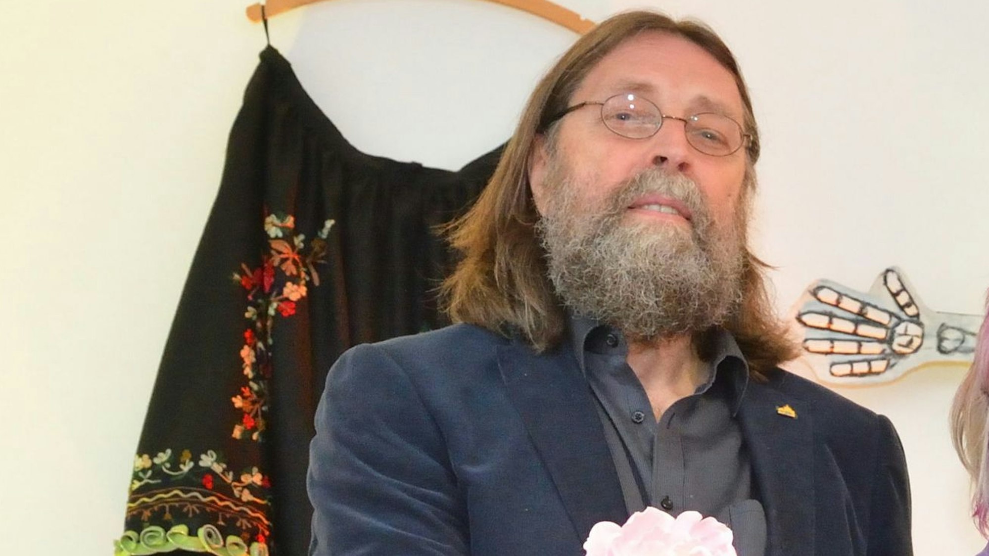 Vize-Bürgermeister Hardy Schumacher (Grüne) steht mit Blumen in der Hand in einem Raum.