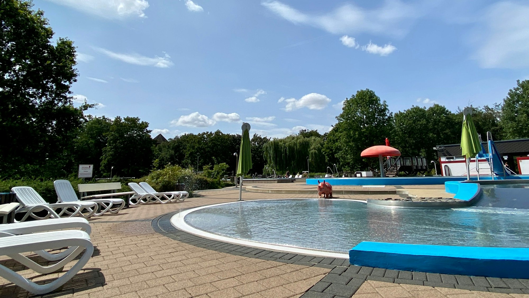 Das Bild zeigt ein verwaistes Freibad, zu sehen ist ein Becken und einige Liegen.