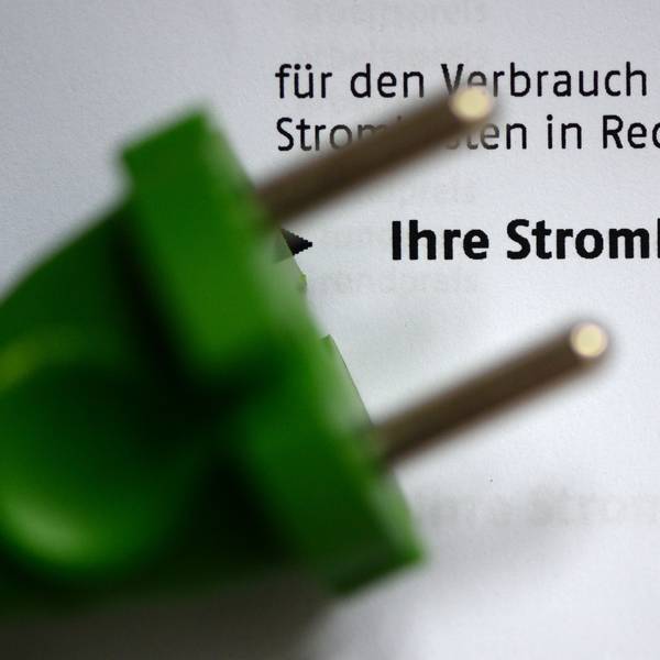 Ein grüner Stromstecker liegt auf einer Stromrechnung.