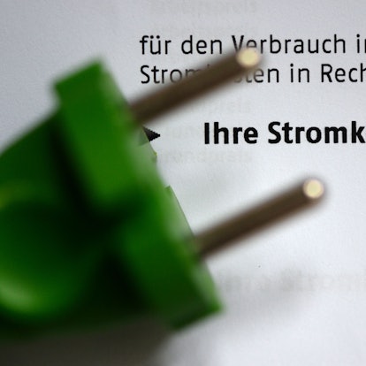Ein grüner Stromstecker liegt auf einer Stromrechnung.