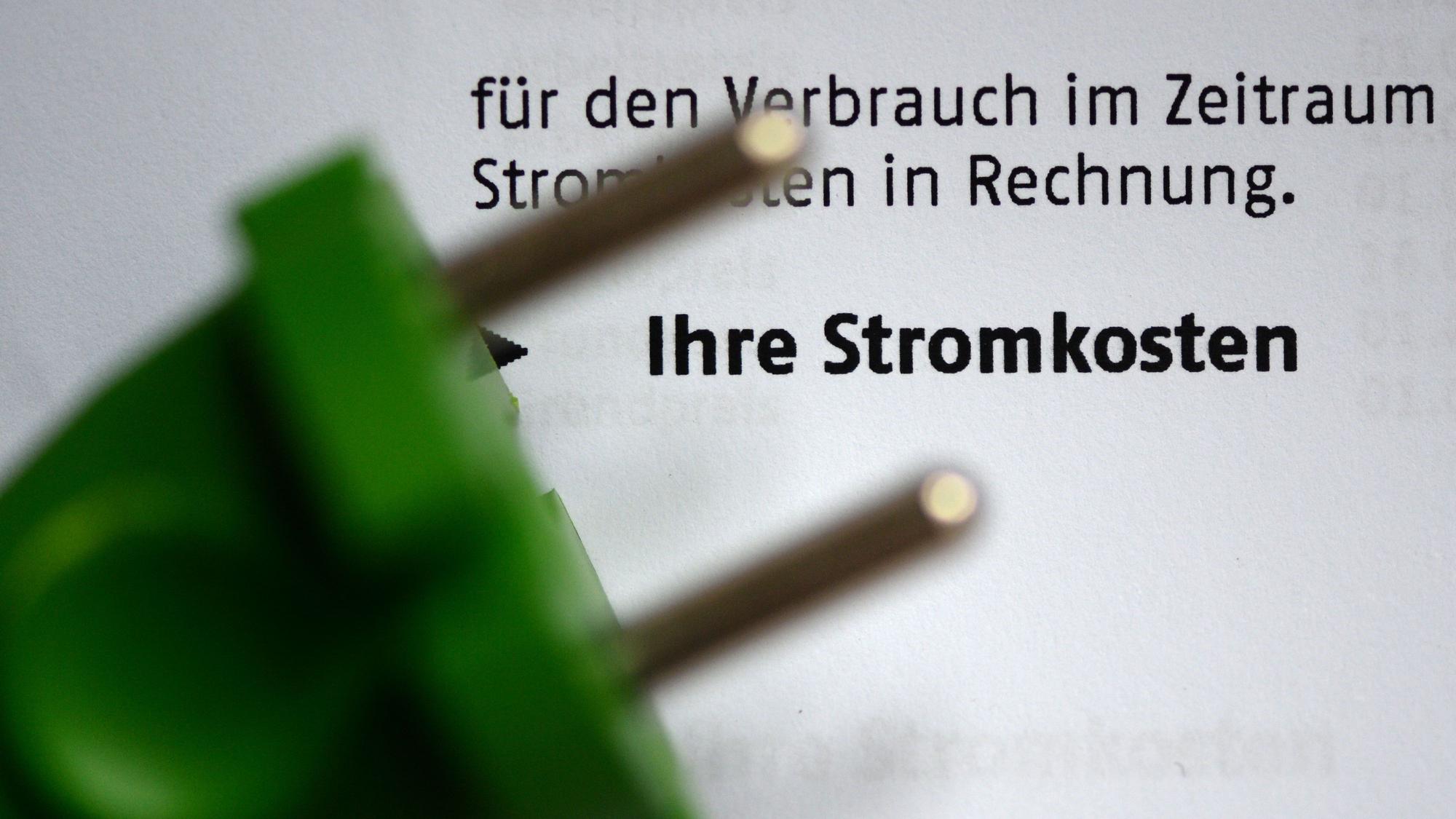 Ein grüner Stromstecker liegt auf einer Stromrechnung.