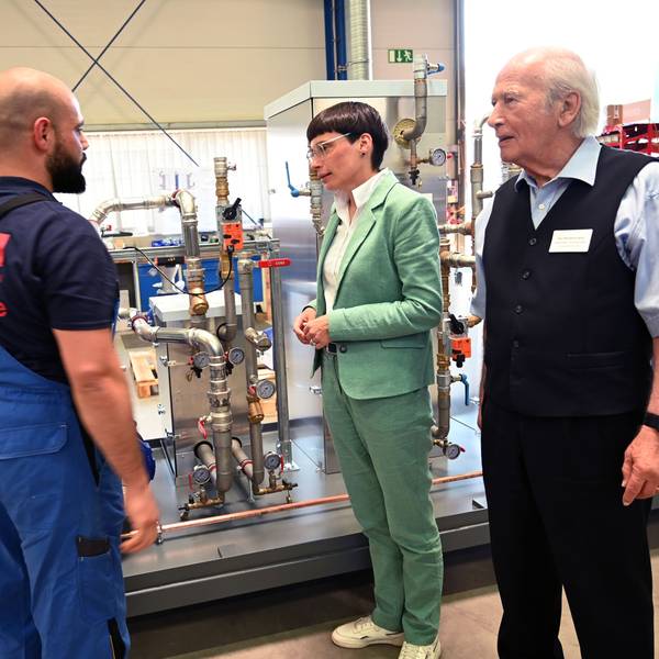 Vor einer Maschine stehen Ministerin Josefine, ONI-Chef Wolfgang Oehm und sein Mitarbeiter Hussein Zeider