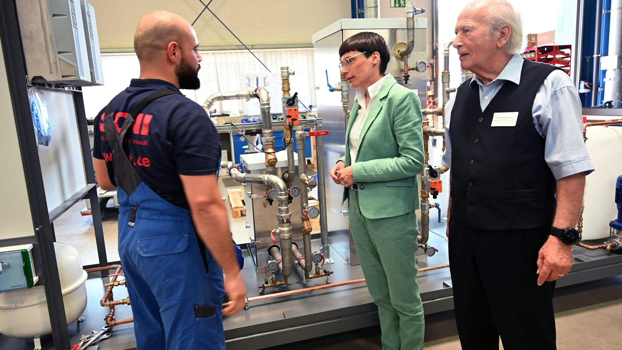 Vor einer Maschine stehen Ministerin Josefine, ONI-Chef Wolfgang Oehm und sein Mitarbeiter Hussein Zeider