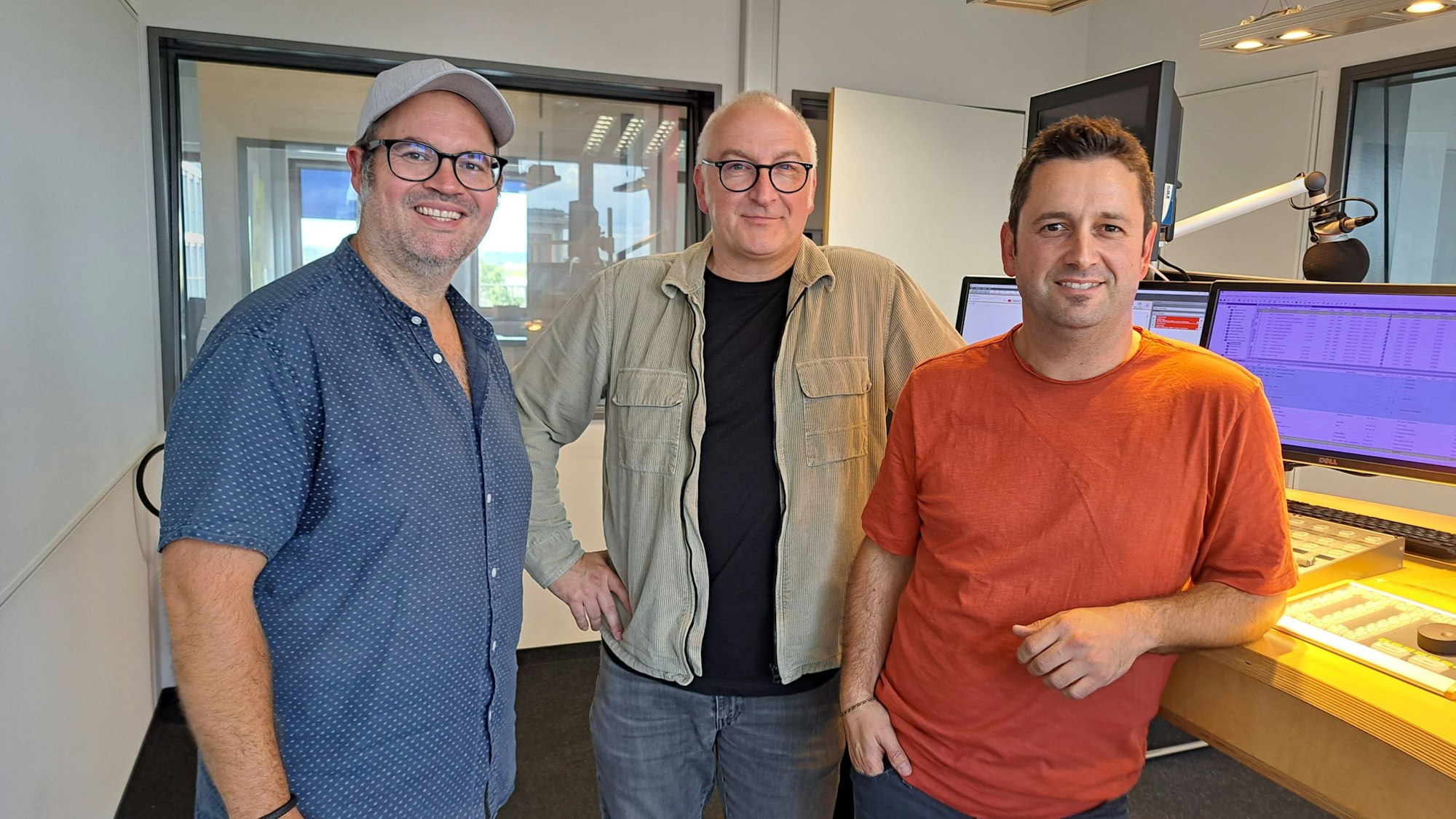 Der Moderator und seine beiden Gäste stehen nebeneinander im Studio.