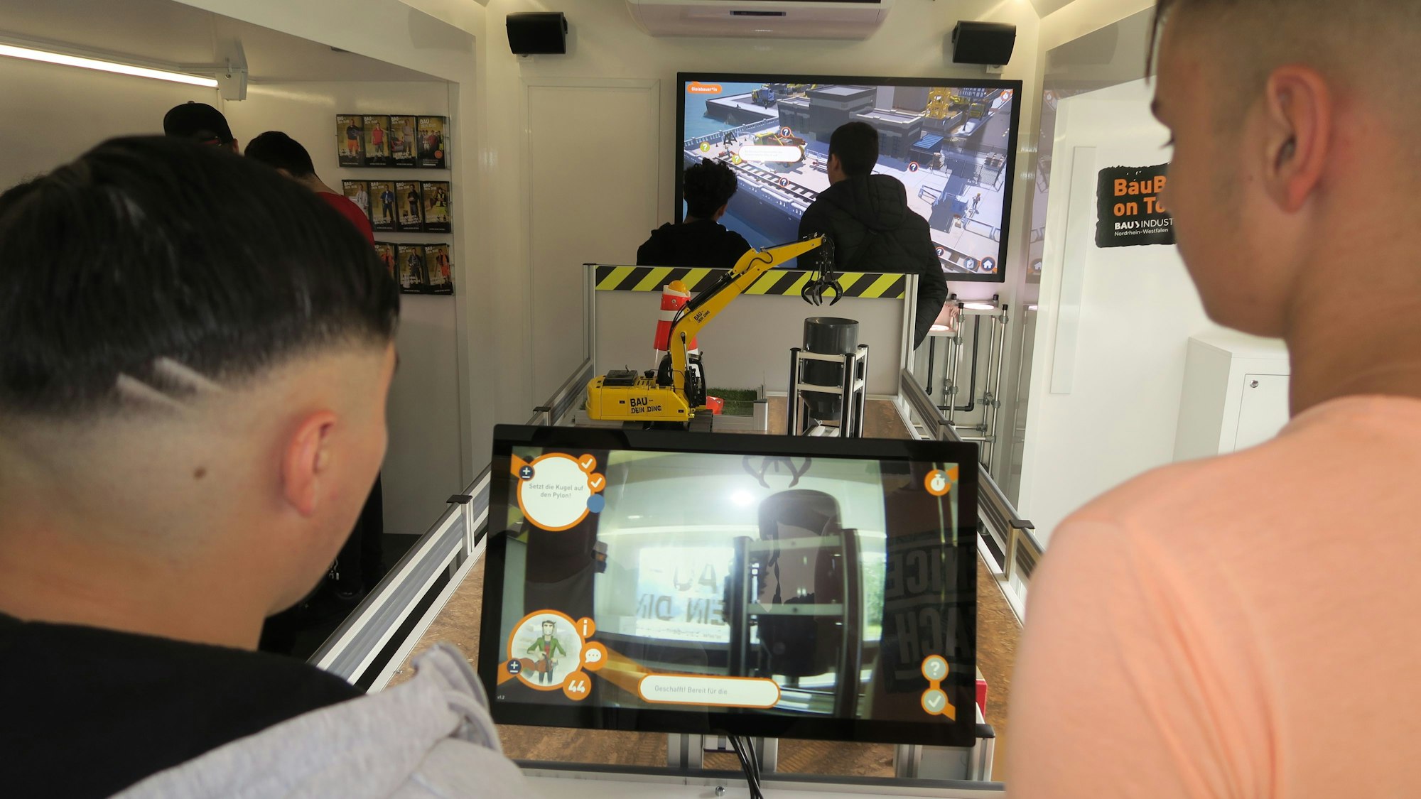 Zwei Schüler steuern einen Bagger.