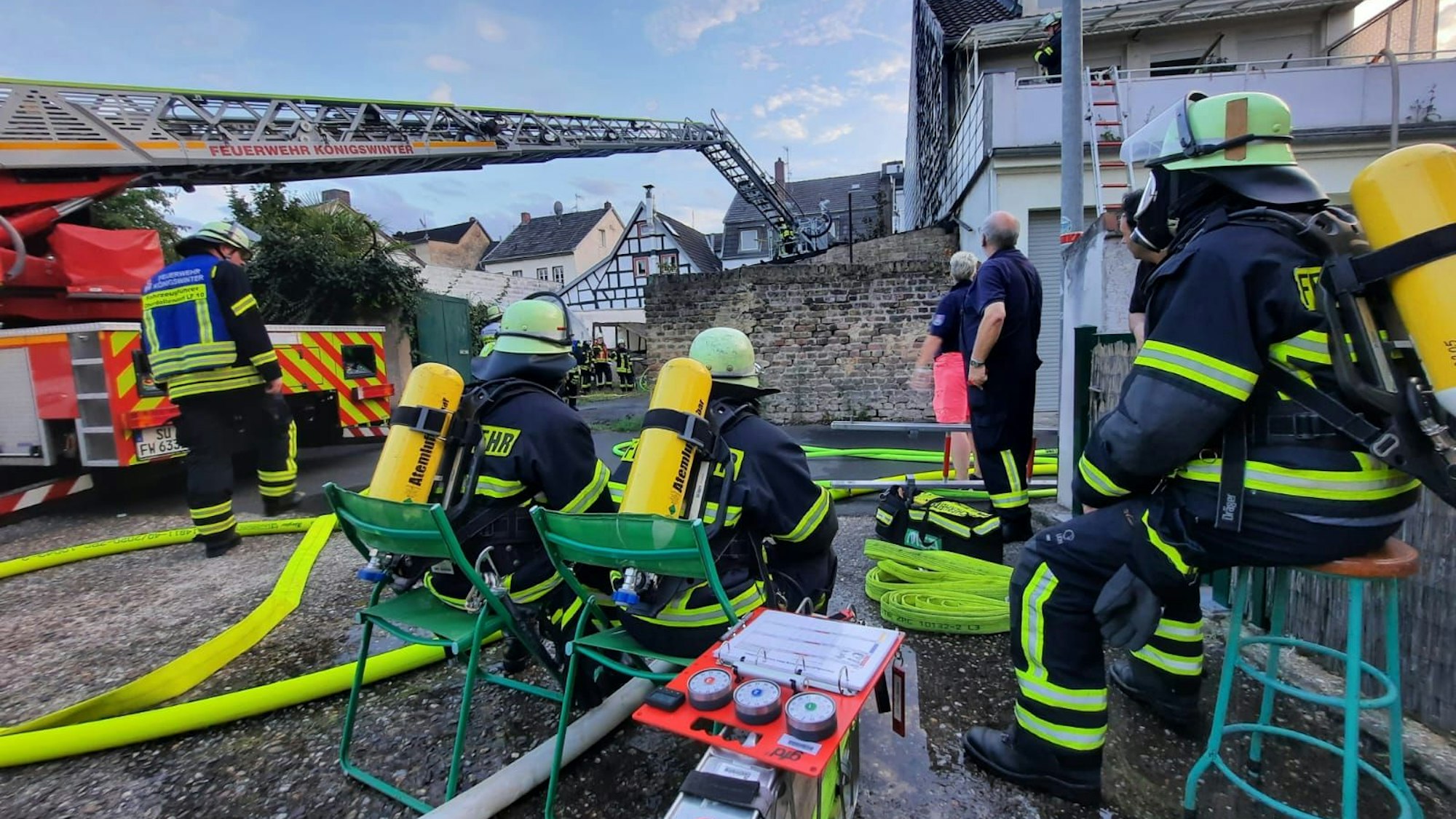 Feuerwehrleute, die Atemschutzgeräte tragen, beobachten den Einsatz der Drehleiter der Feuerwehr.