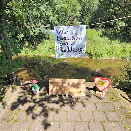 Auf dem Aufgang zur abgerissenen Brücke in Mauel hängt an einer Kordel ein Schild der Anwohner mit der Aufschrift „Wir brauchen den Fluchtweg“.