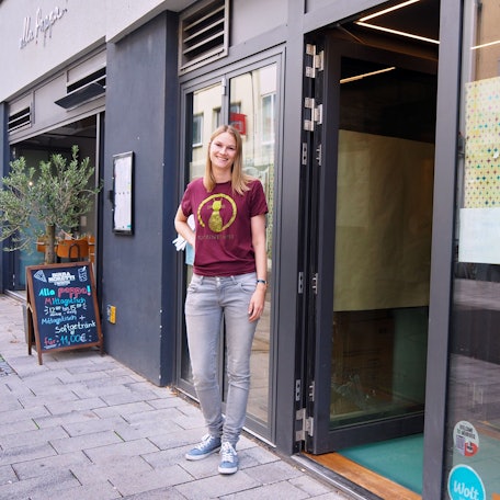 Die Betreiberin steht vor dem Geschäftseingang.