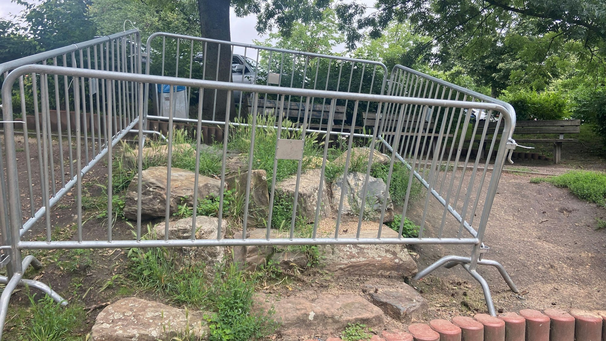 Vier Drängelgitter sperren ein Areal mit großen Steinen ab.