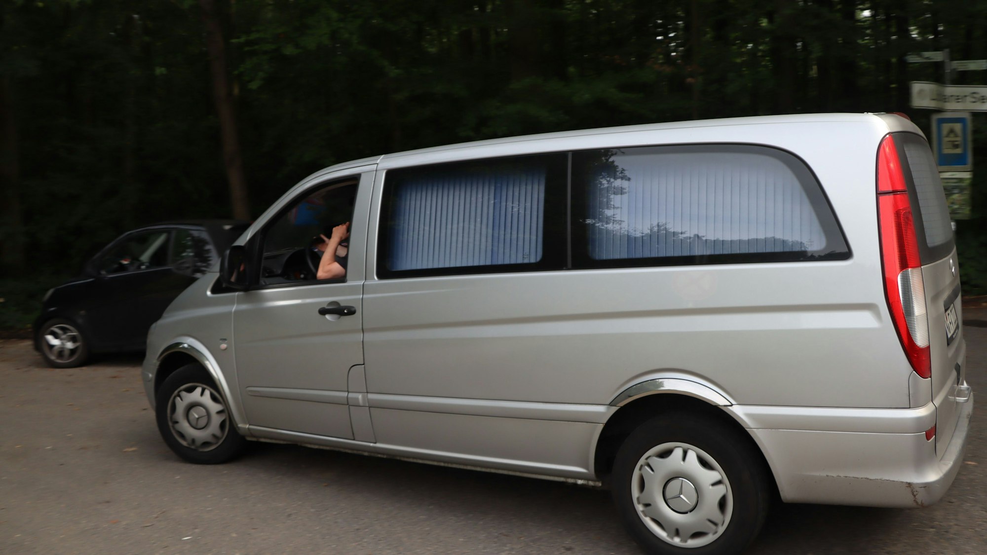 Ein Leichenwagen an der Zufahrt zu einem Waldstück.
