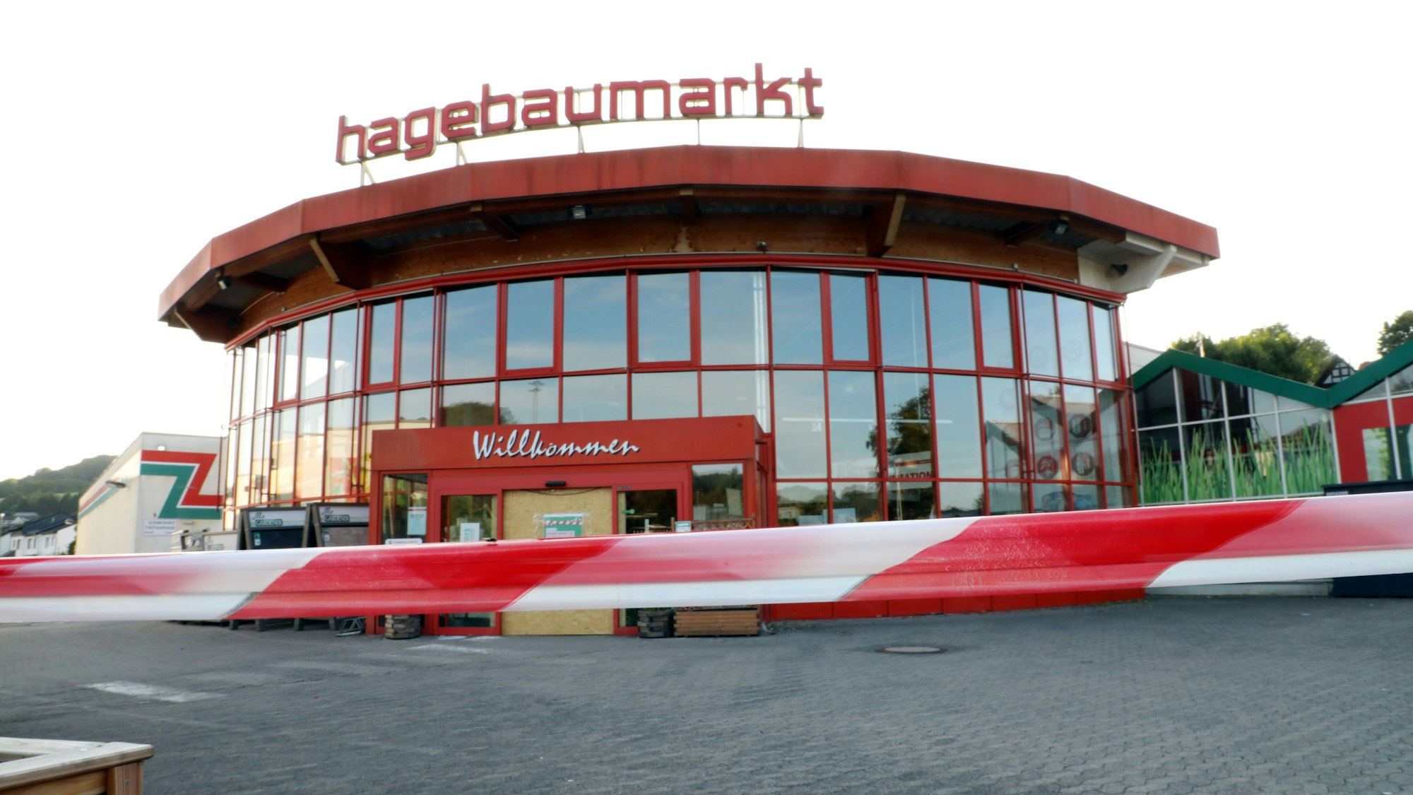 Vor dem Eingangsgebäude des Hagebaumarkts Overath ist ein rot-weißes Flatterband gespannt.