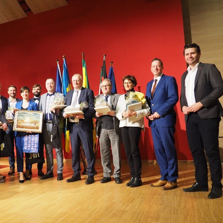 Viele Menschen stehen im Halbkreis auf der Bühne. 1