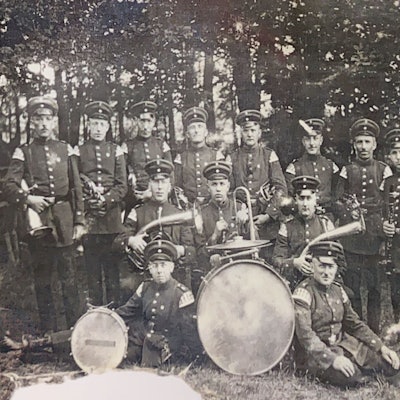 Das historische Bild zeigt eine Blaskapelle mit Instrumenten.
