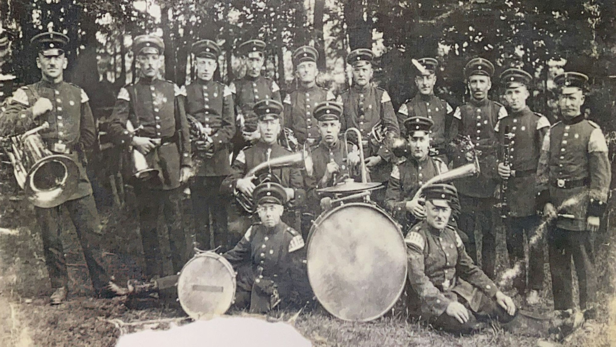 Das historische Bild zeigt eine Blaskapelle mit Instrumenten.