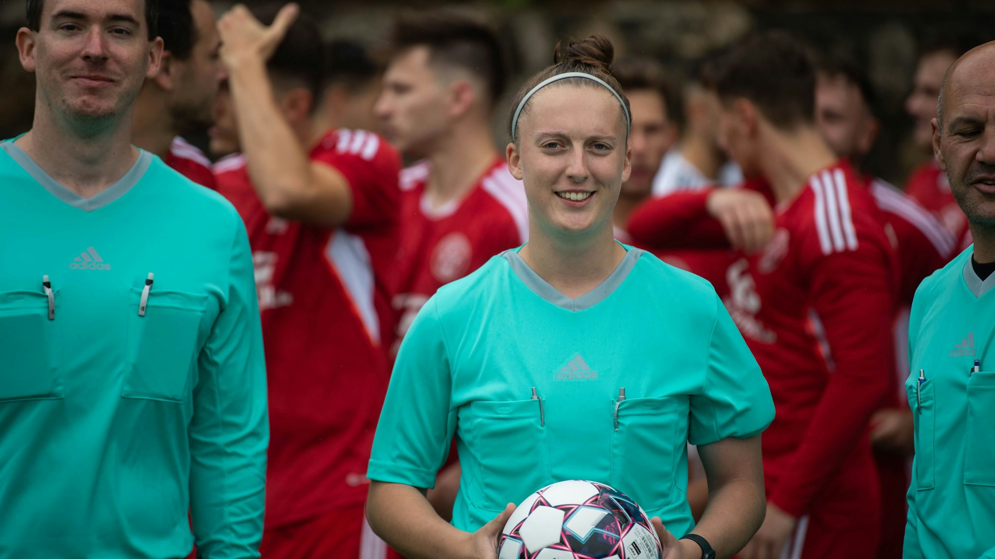 Das Schiedsrichtergespann blickt in die Kamera. Schiedsrichterin Lisa Reinecke trägt einen Ball.