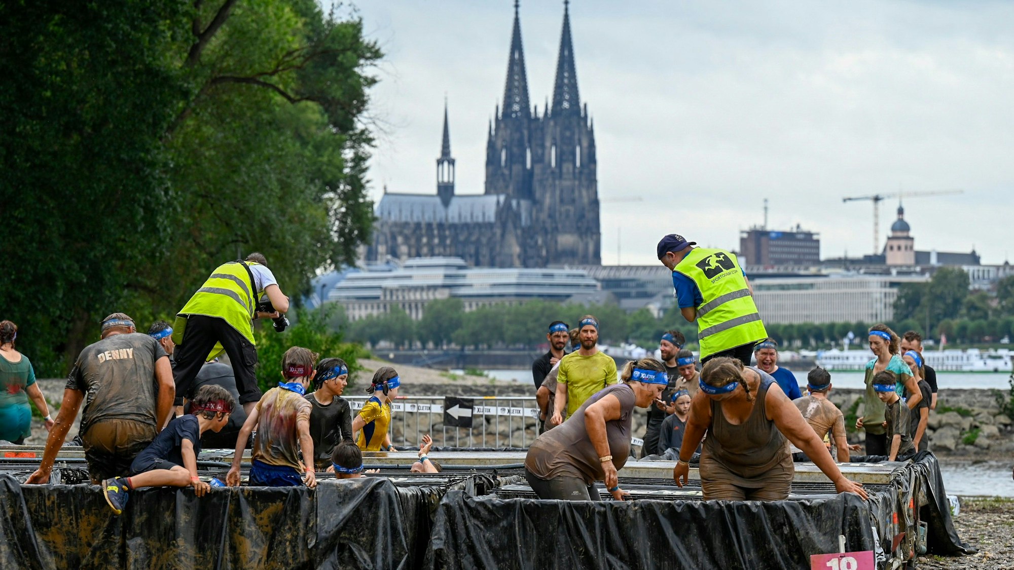 Kinder und Erwachsene gehen durch ein Schlammbecken im Kölner Jugendpark.