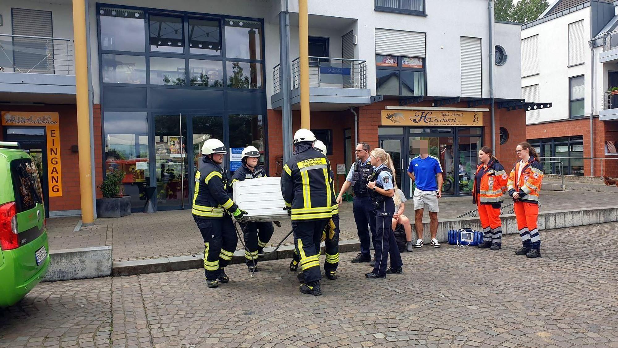 Feuerwehrleute tragen eine Waschmaschine.