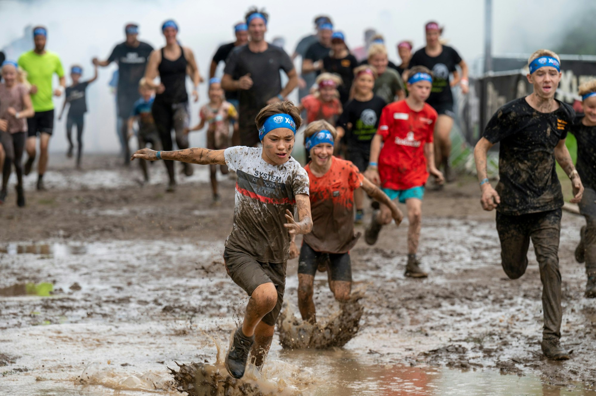 Kinder rennen durch Schlammpfützen.