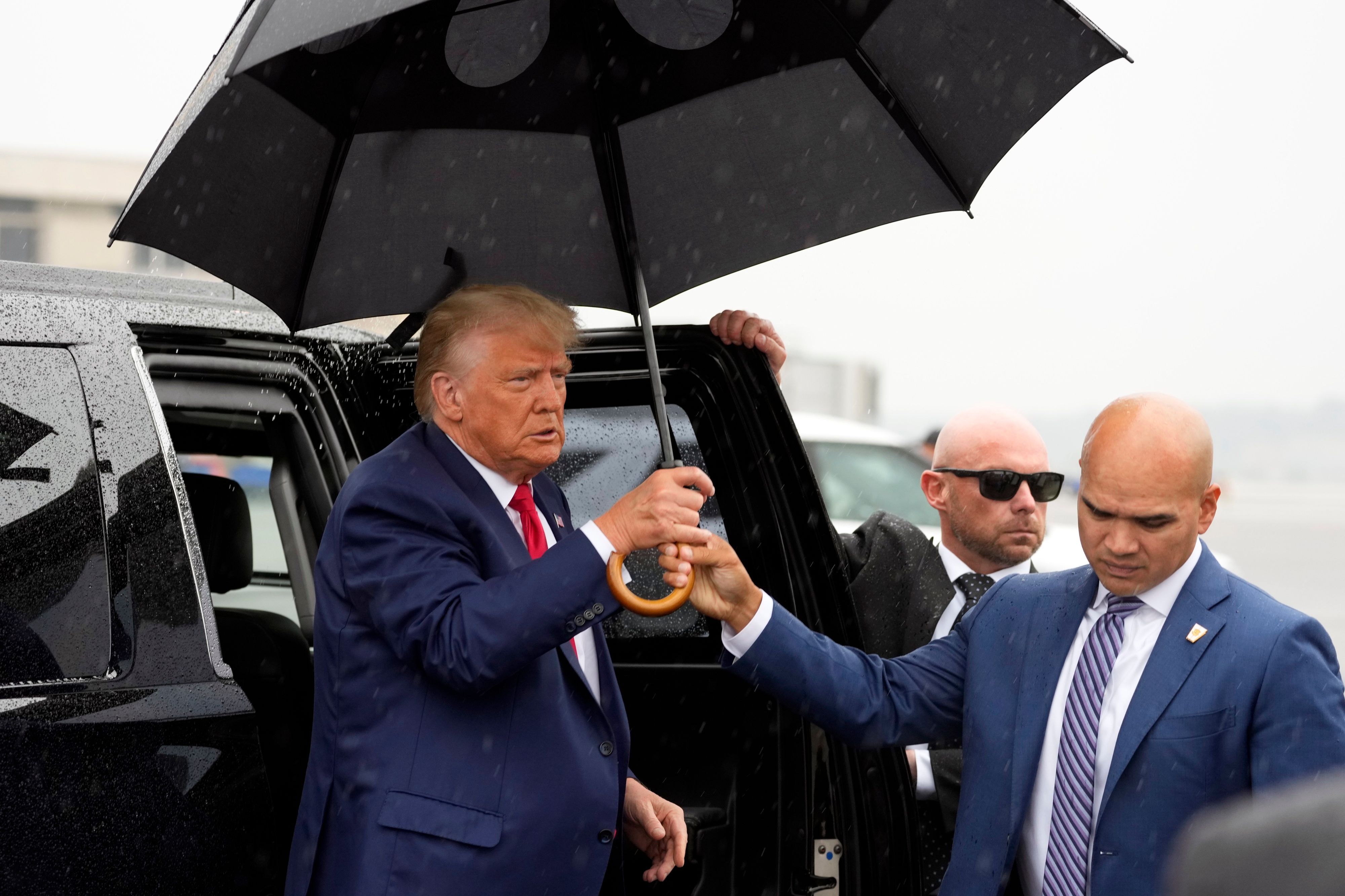 Walt Nauta (r), Leibwächter des Ex-US-Präsidenten Trump, reicht Donald Trump (l), ehemaliger Präsident der USA, einen Regenschirm, bevor er am Ronald Reagan Washington National Airport eine Rede hält.