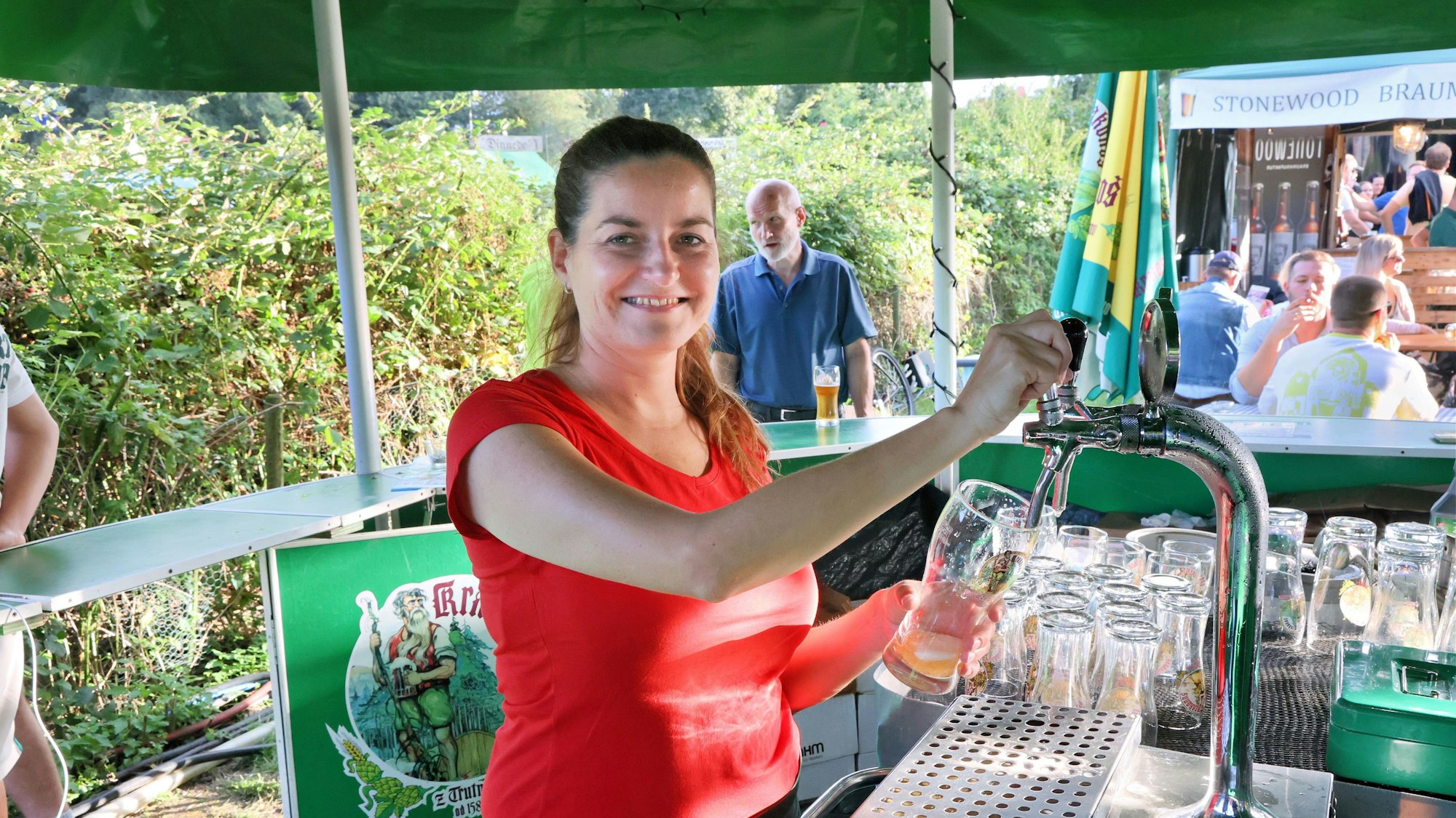 Eine Frau zapft Bier an einem Stand der Opladener Bierbörse.