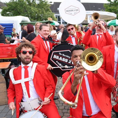 Eine mobile Blaskapelle in roten Anzügen posiert für den Fotografen.