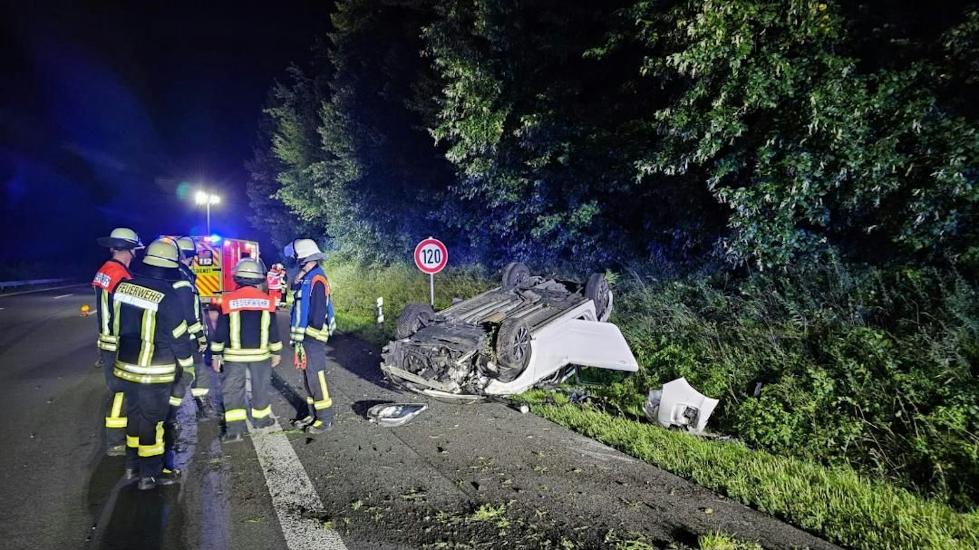 Ein weißes Auto liegt nach einem Unfall auf dem Dach im Straßengraben.