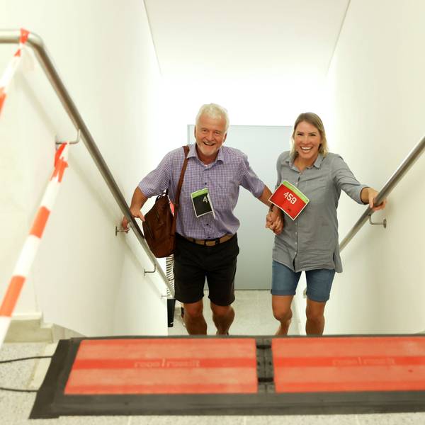 Ein Mann und eine Frau kommen lachend und händchenhaltend eine Treppe hinauf.