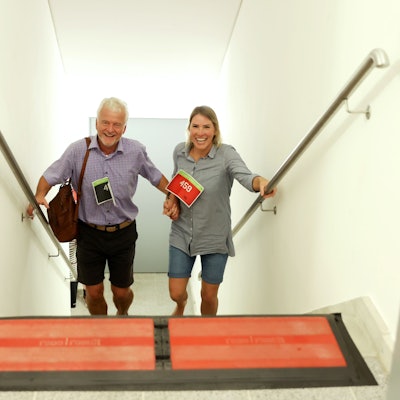 Ein Mann und eine Frau kommen lachend und händchenhaltend eine Treppe hinauf.