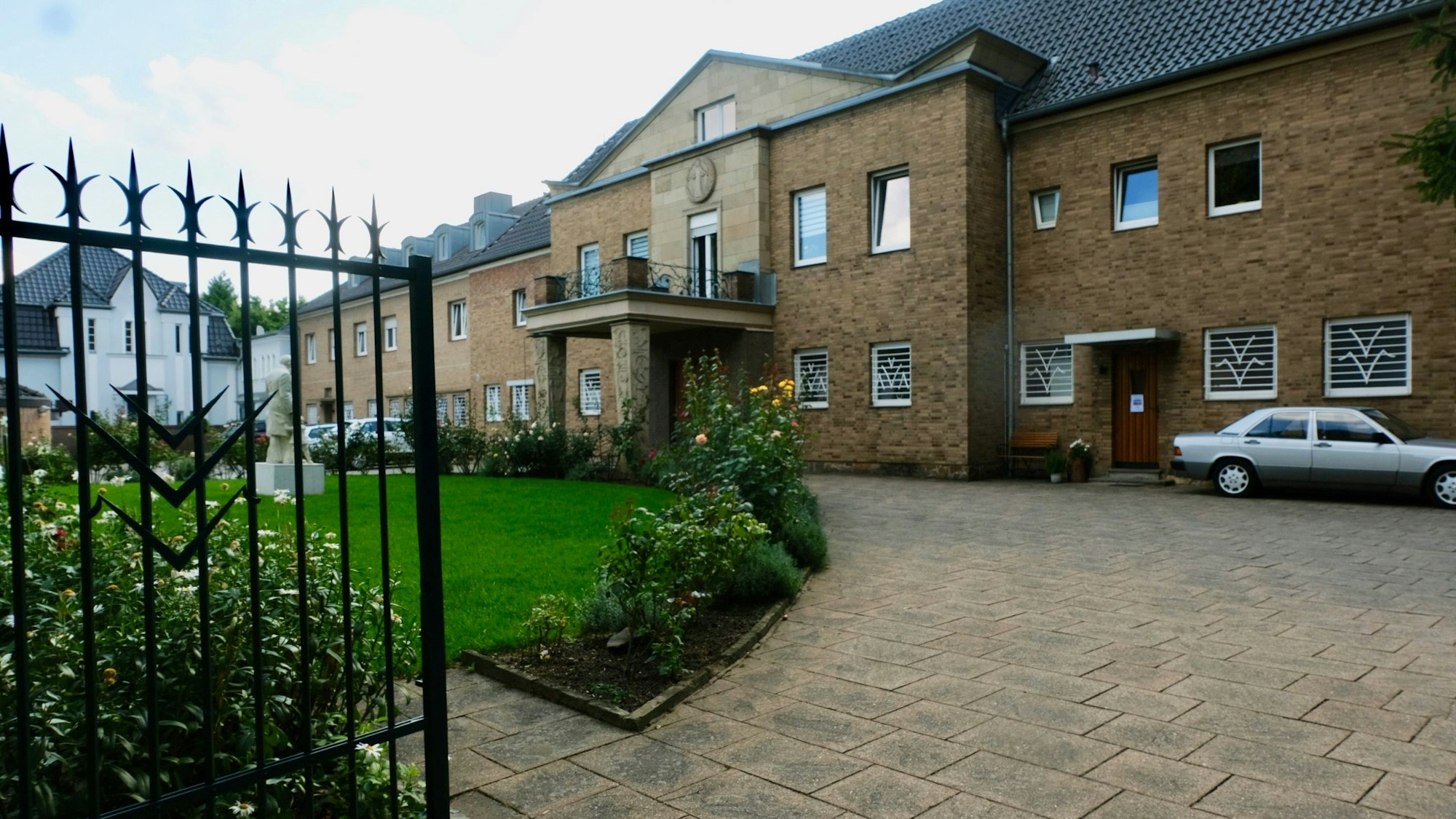 Ein großes Gebäude mit Vorgarten und Auffahrt ist zu sehen.
