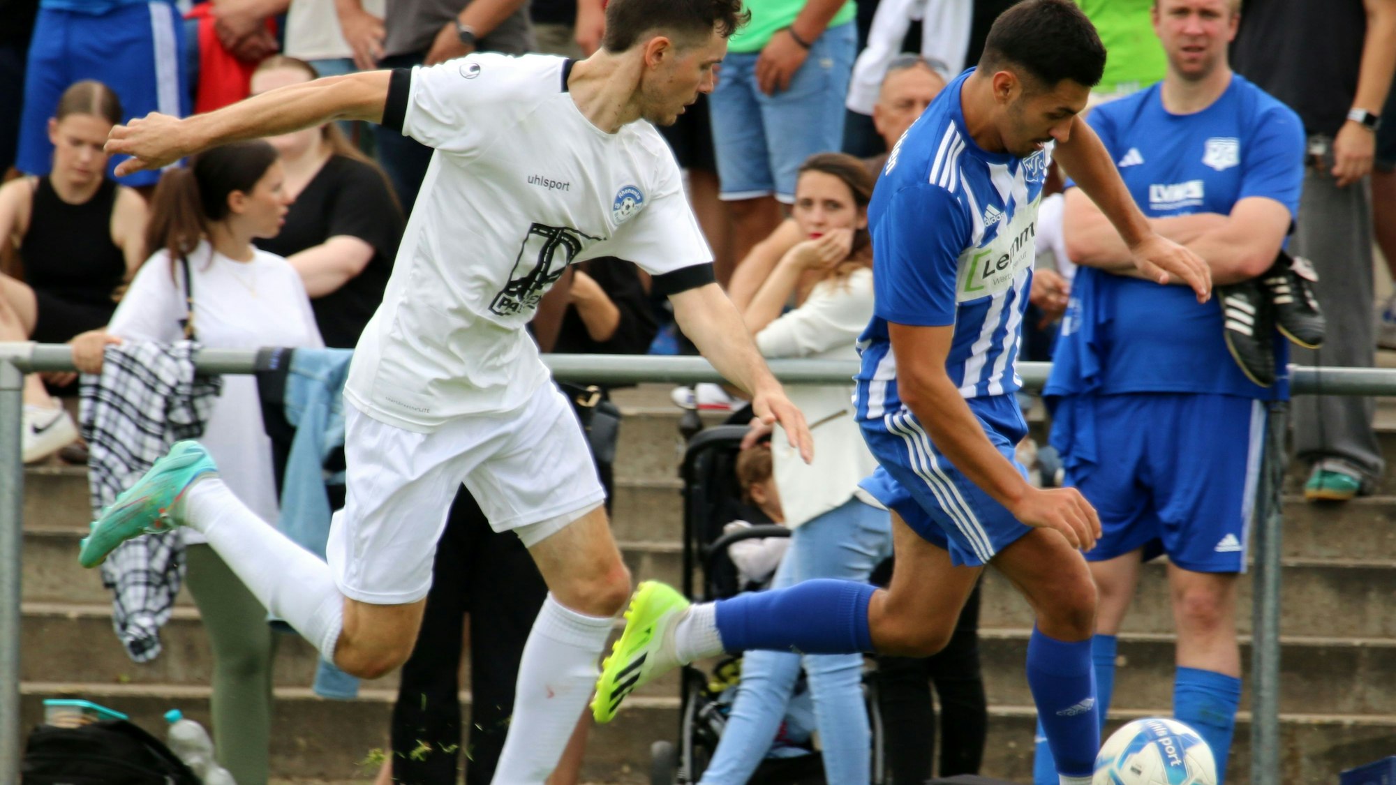 Das Bild zeigt zwei Fußballer, die sich an der Seitenlinie ein Laufduell liefern.