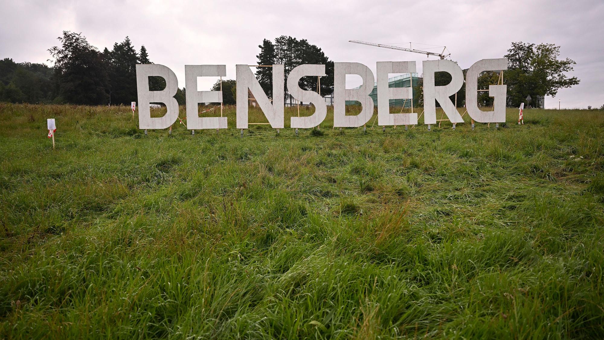 Das Foto zeigt die Kunstinstallation „Bensberg“: Weiße Buchstaben wie die des Hollywood-Schriftzugs auf einer grünen Wiese.