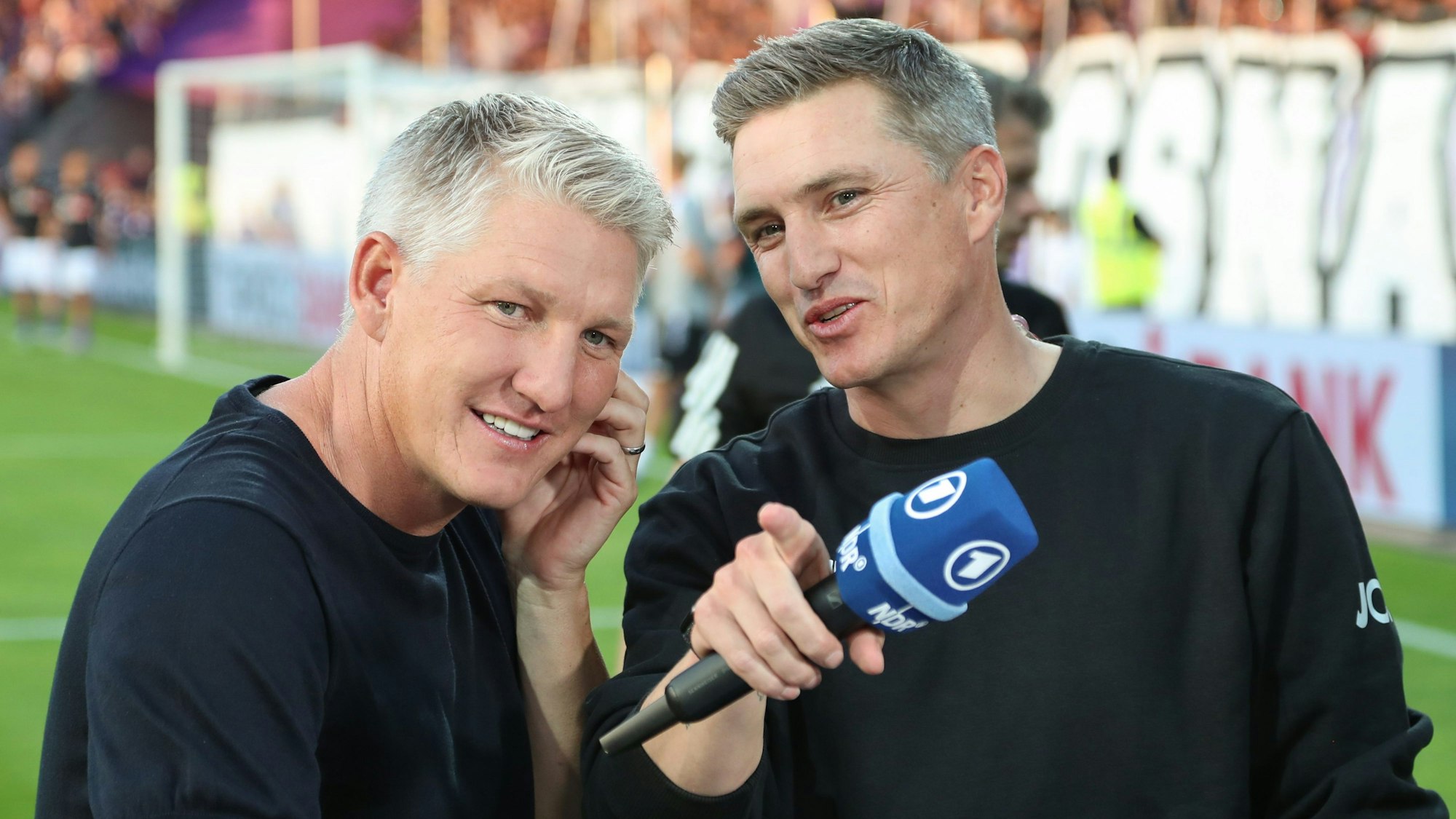 Osnabrücks Trainer Tobias Schweinsteiger (r) steht vor Spielbeginn neben seinem Bruder Bastian Schweinsteiger, der für den übertragenden Fernsehsender ARD als TV-Experte arbeitet.