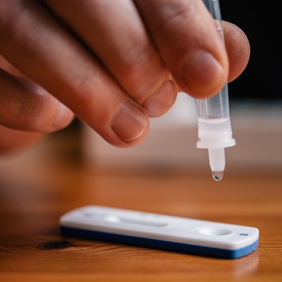 Ein Mann träufelt eine Lösung auf eine Testkassette, die von Covid-19 verursachte Antigene nachweisen kann (gestellte Szene).