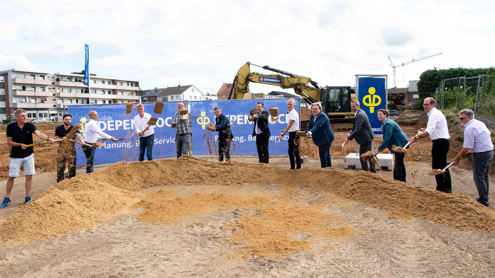 Vertreter der Stadt Euskirchen und der beteiligten Unternehmen vollziehen den symbolischen Spatenstich, indem sie Sand durch die Luft werfen.