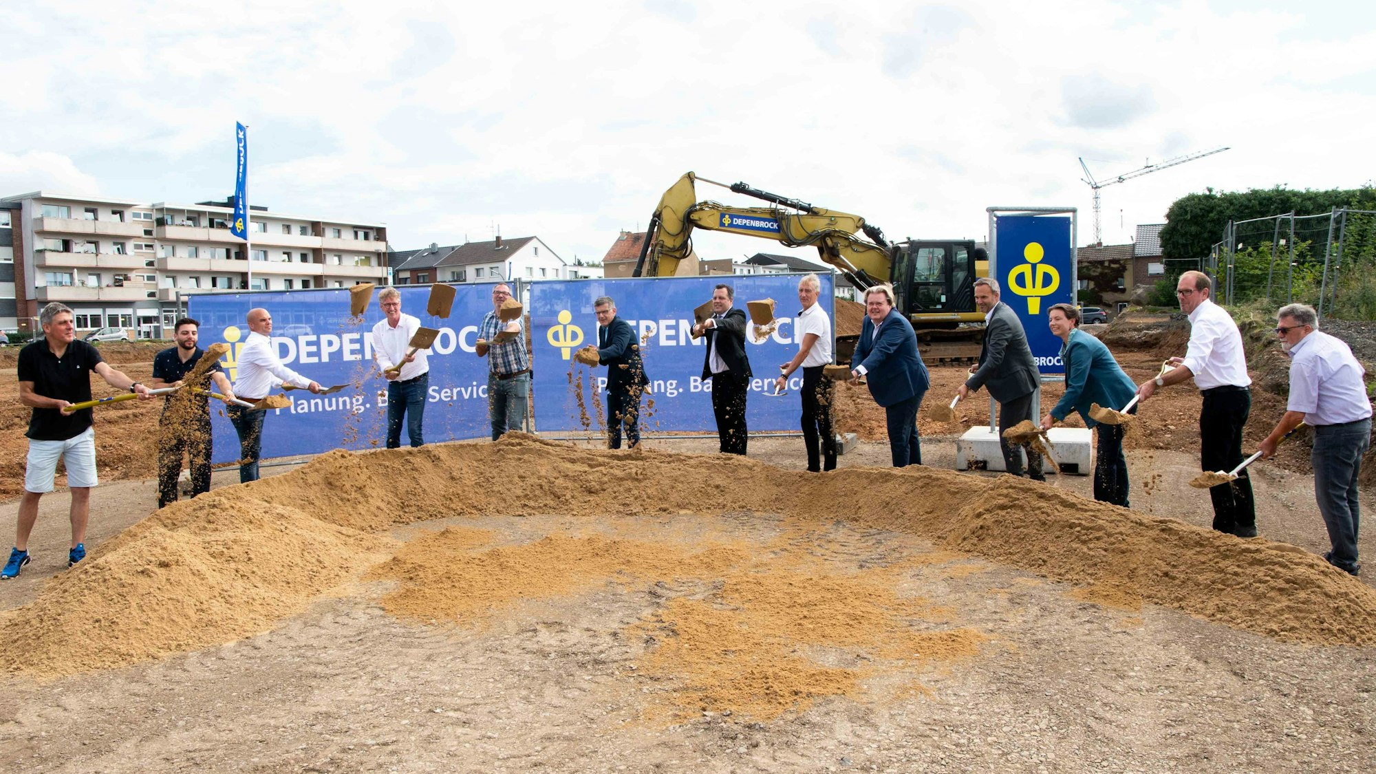 Vertreter der Stadt Euskirchen und der beteiligten Unternehmen vollziehen den symbolischen Spatenstich, indem sie Sand durch die Luft werfen.