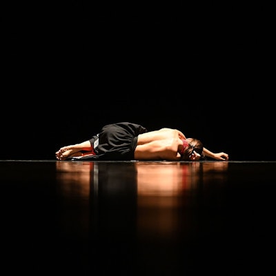 Eine Frau mit entblößtem Rücken liegt auf einer spiegelnden Oberfläche.