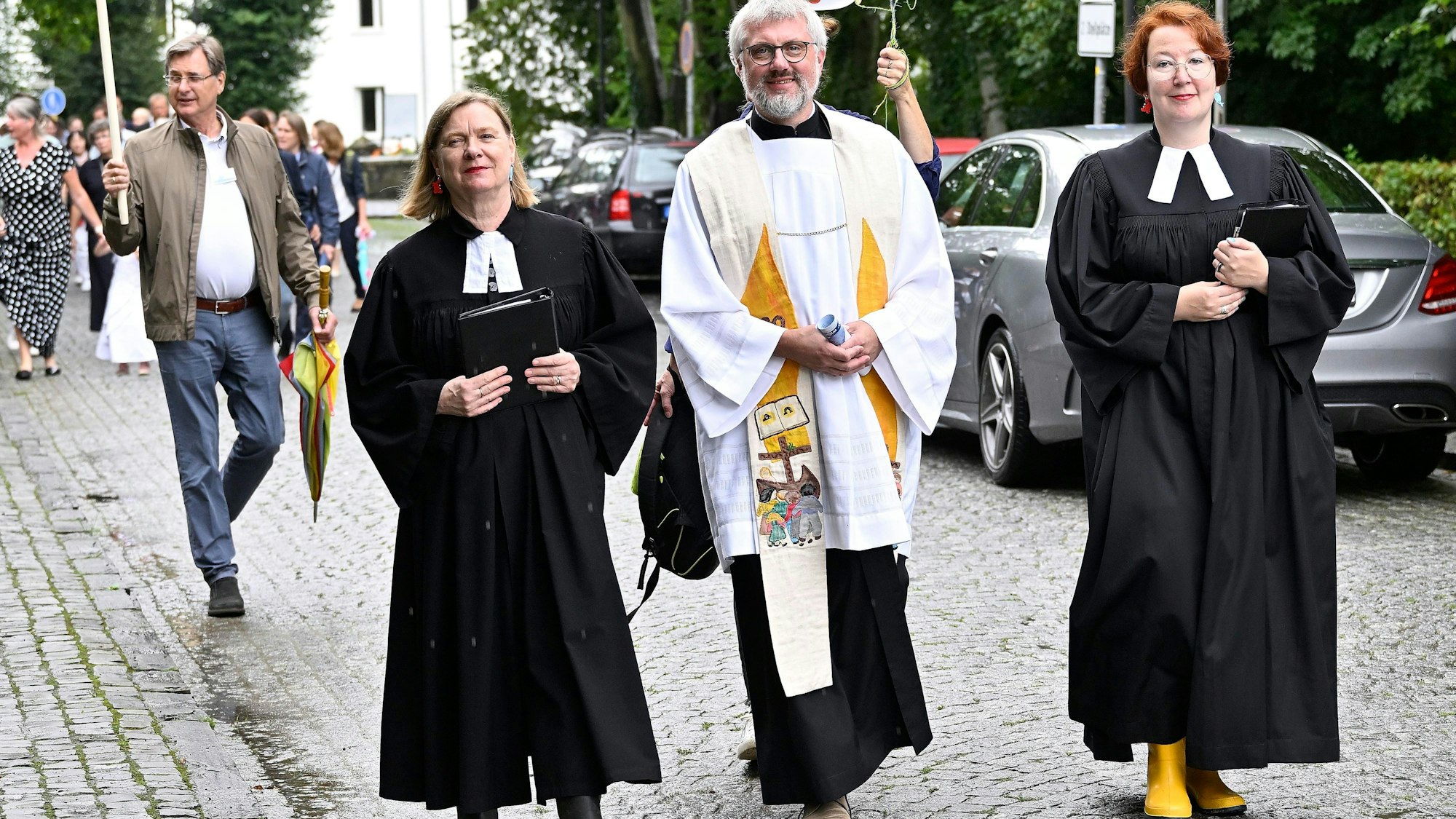 Pfarrerinnen auf dem Weg zur Taufe von 14 Kindern in und an der Dhünn mit Flusswasser.