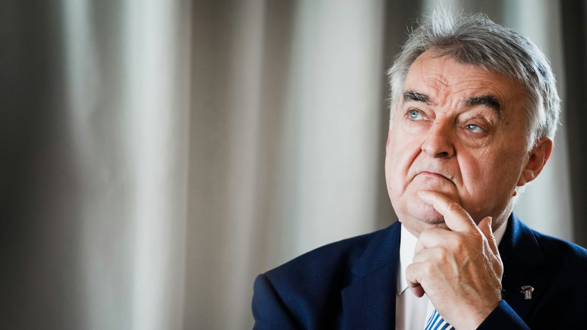 NRW-Innenminister Herbert Reul im Portrait - er blickt versonnen in die Ferne, hinter ihm ist ein beschatteter Vorhang zu sehen.