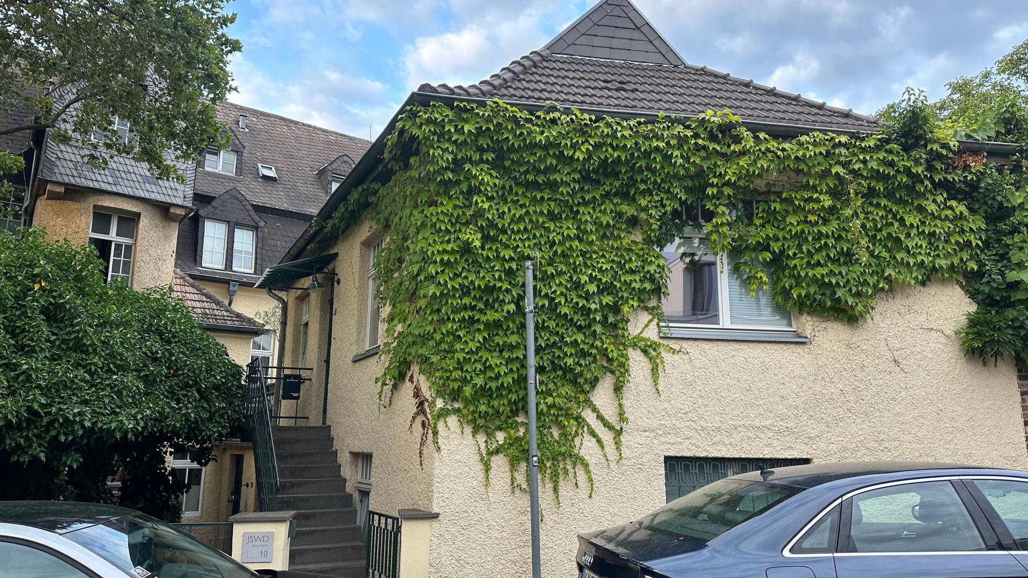 Ein kleines Haus ist einem größeren vorgelagert.