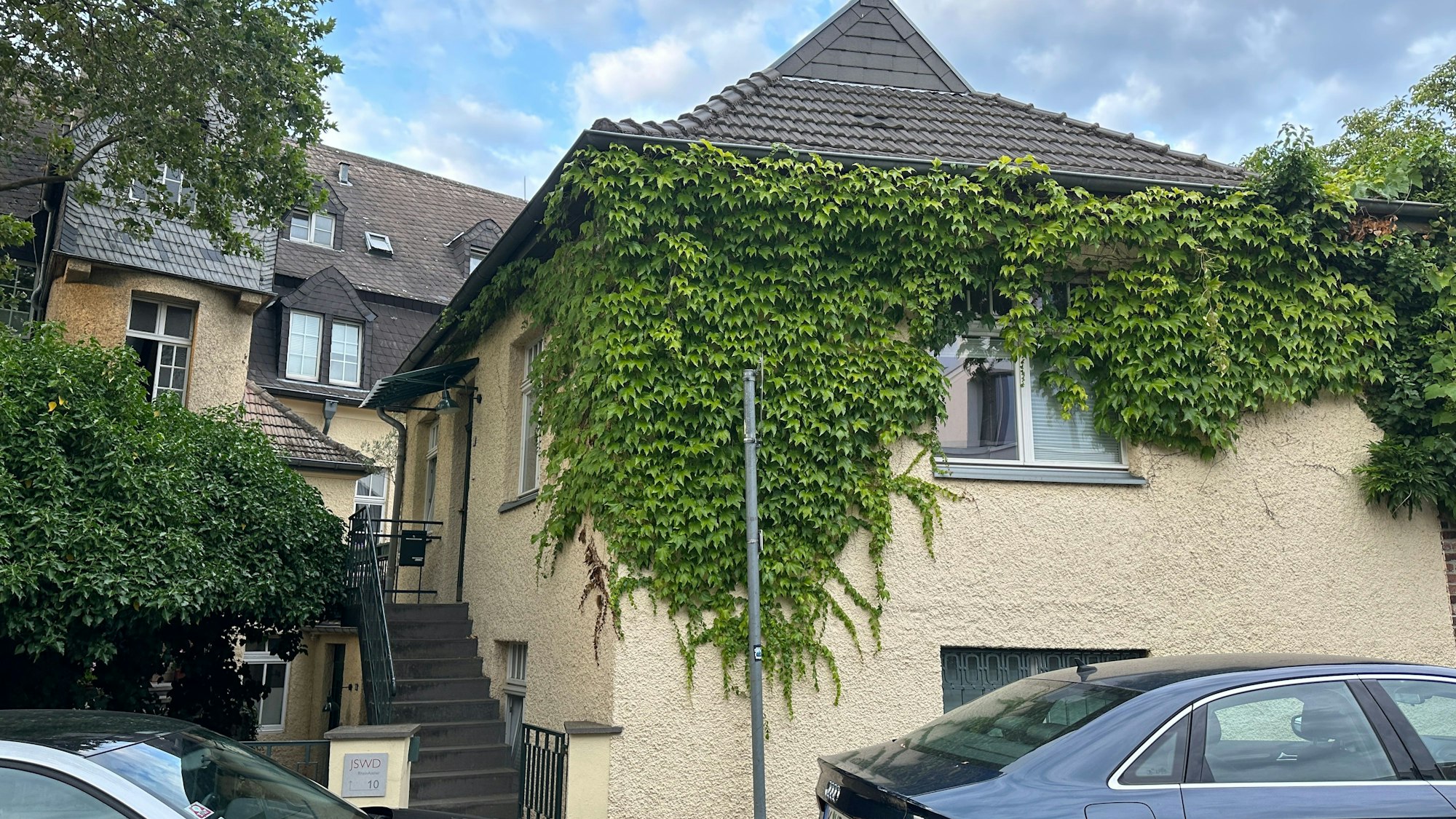 Ein kleines Haus ist einem größeren vorgelagert.