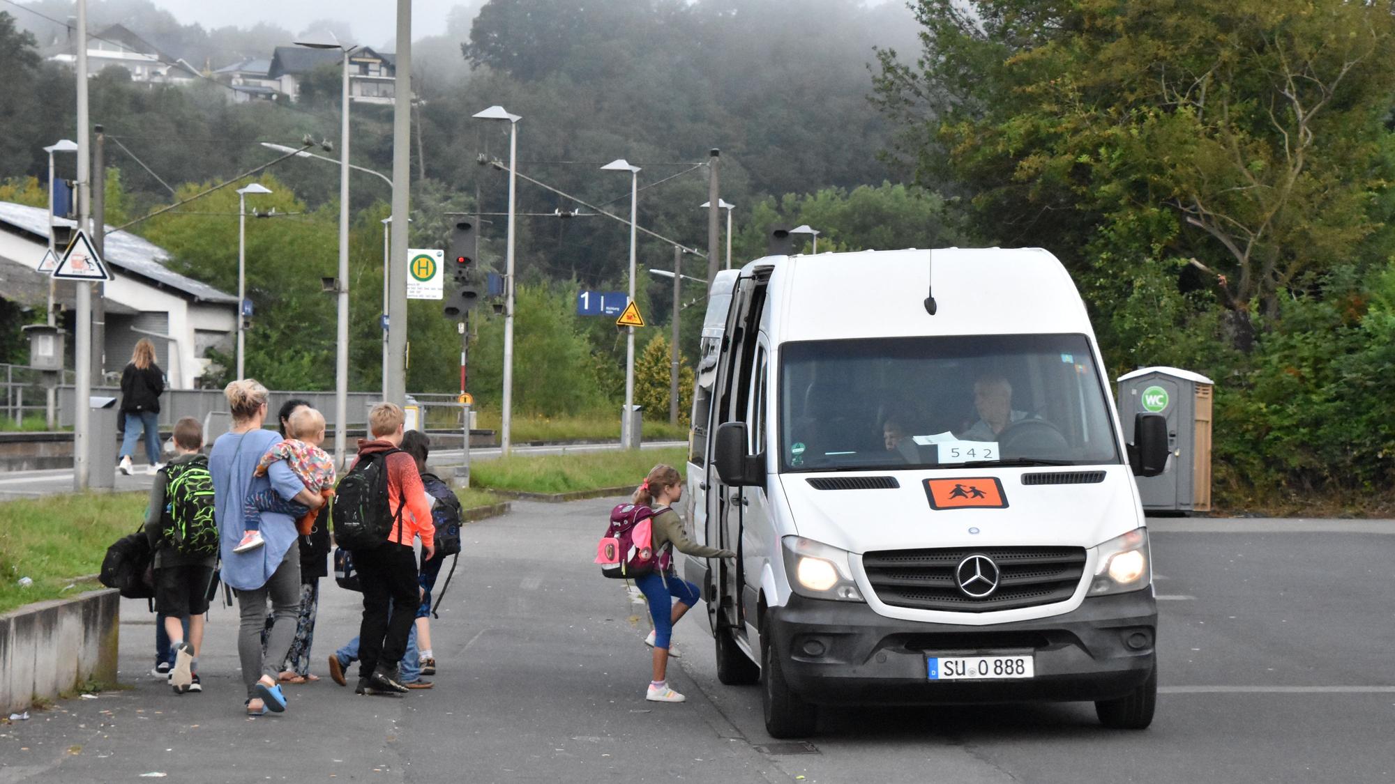 Kinder steigen in einen Kleinbus ein.