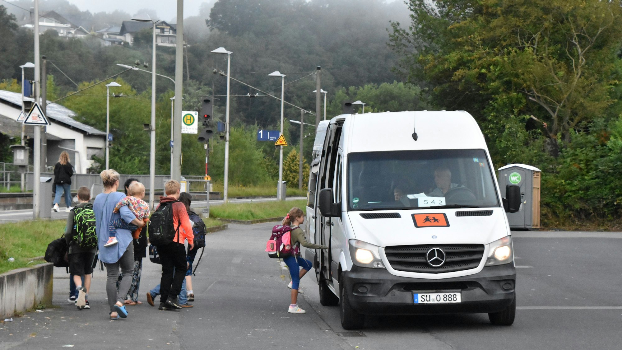 Kinder steigen in einen Kleinbus ein.