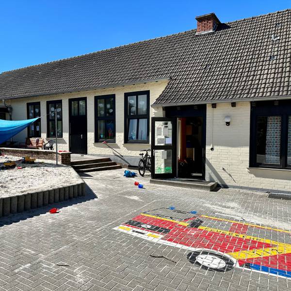Das Außengelände einer Kita mit Sandkasten und Pflastermosaik.