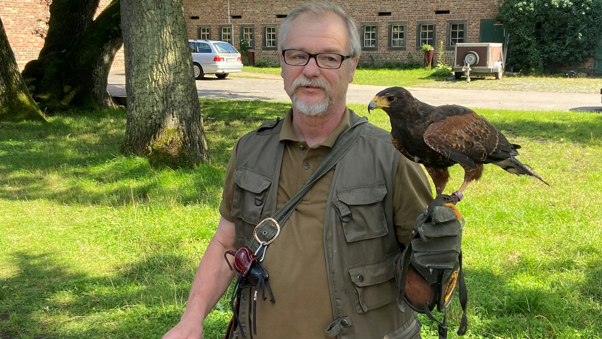 Auf der Hand des Falkners sitzt der Vogel.