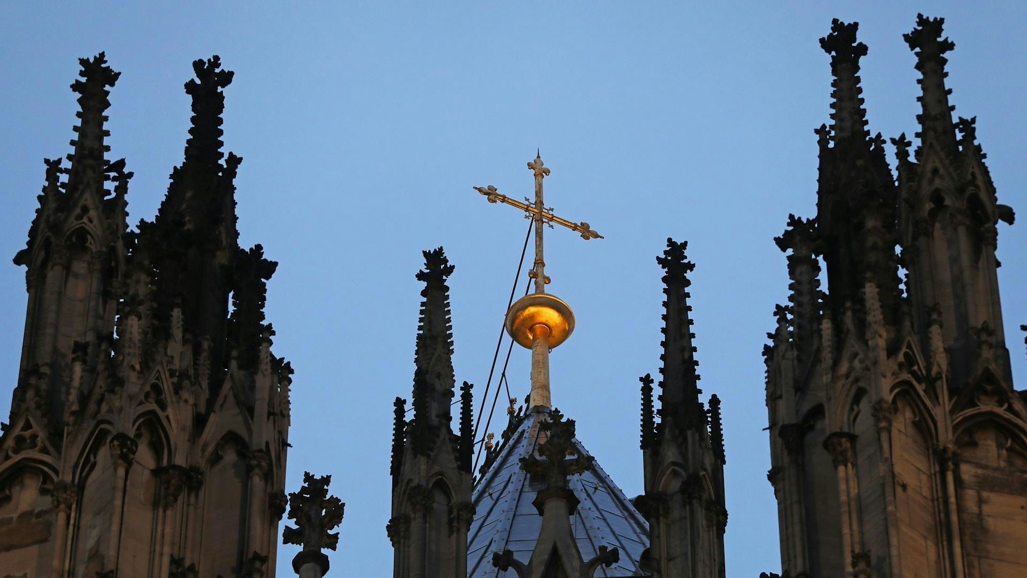 Ein Kreuz steht hinter dem Strebewerk am Dom.