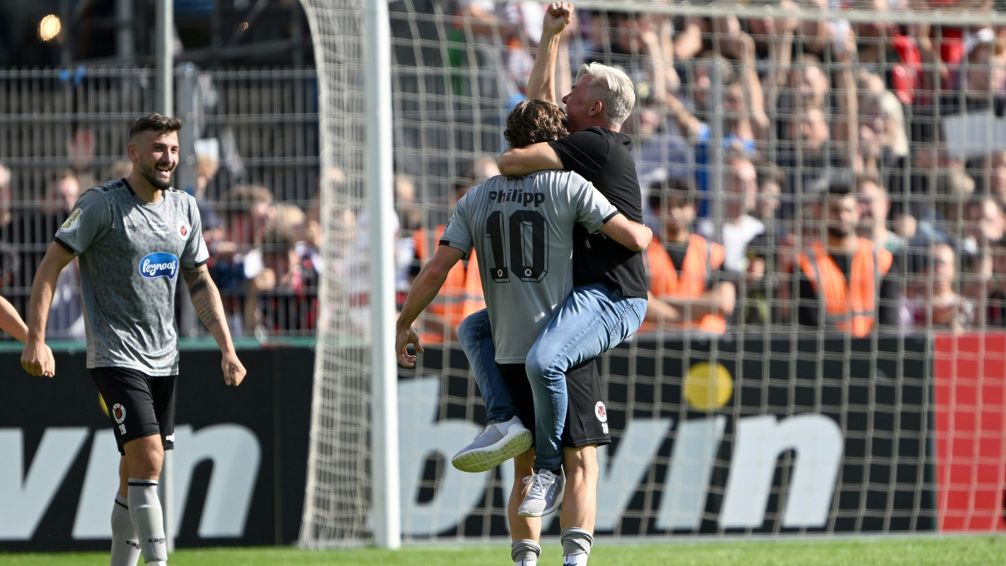 12.08.2023, Nordrhein-Westfalen, Köln: Fußball: DFB-Pokal, Viktoria Köln - Werder Bremen, 1. Runde, Sportanlage Höhenberg. Kölns David Philipp (l) und sein Trainer Olaf Janßen feiern den 3:2-Sieg über Werder Bremen. Foto: Federico Gambarini/dpa - WICHTIGER HINWEIS: Gemäß den Vorgaben der DFL Deutsche Fußball Liga bzw. des DFB Deutscher Fußball-Bund ist es untersagt, in dem Stadion und/oder vom Spiel angefertigte Fotoaufnahmen in Form von Sequenzbildern und/oder videoähnlichen Fotostrecken zu verwerten bzw. verwerten zu lassen. +++ dpa-Bildfunk +++