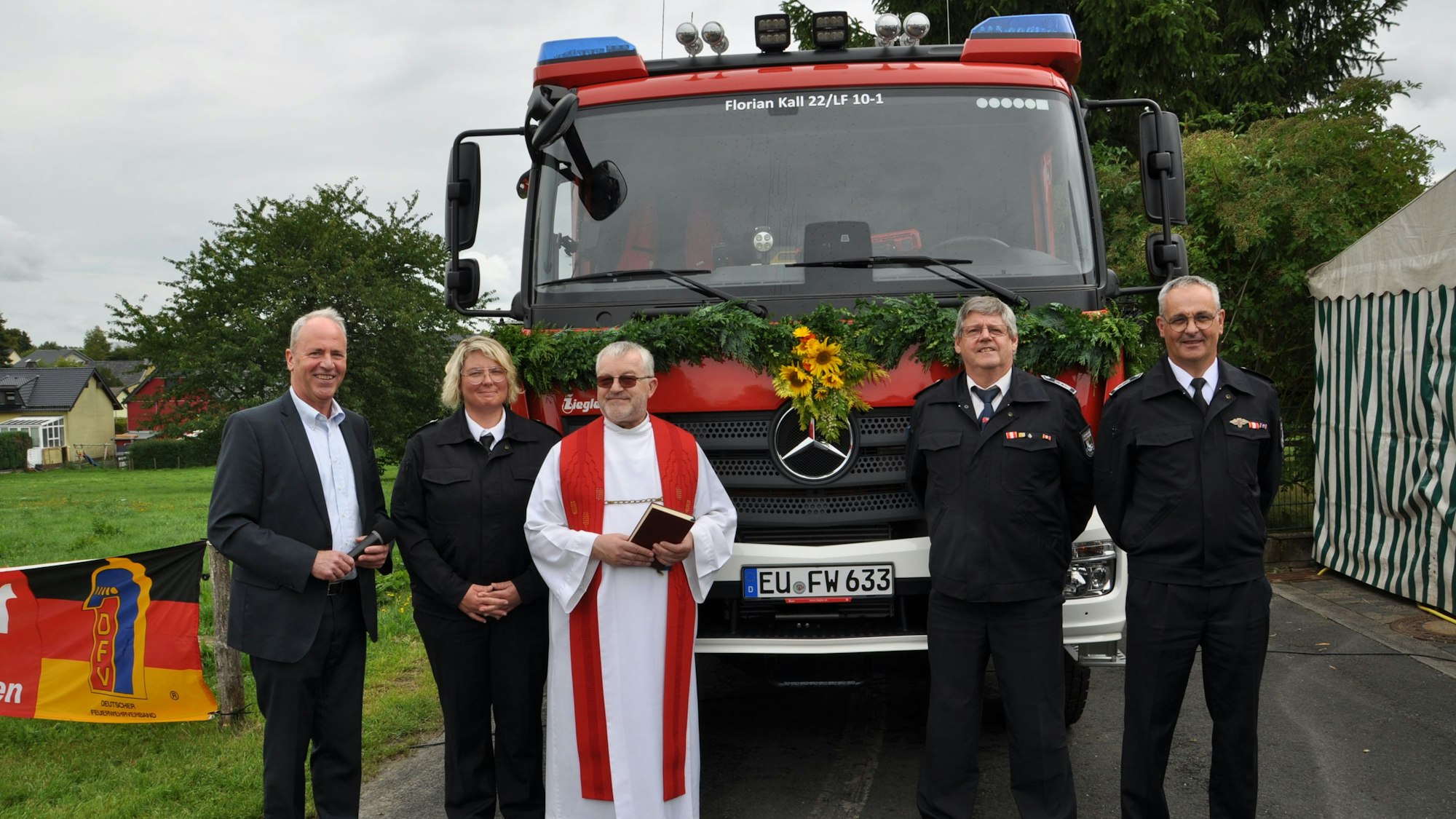 Bürgermeister Hermann-Josef Esser (v.l.), Löschgruppenführerin Kerstin Brandhoff, Pfarrer Wieslaw Kaczor, Gemeindewehrleiter Harald Heinen und dessen Stellvertreter Andreas Lang stehen vor einem mit Blumen geschmückten, neuen Löschgruppenfahrzeug.
