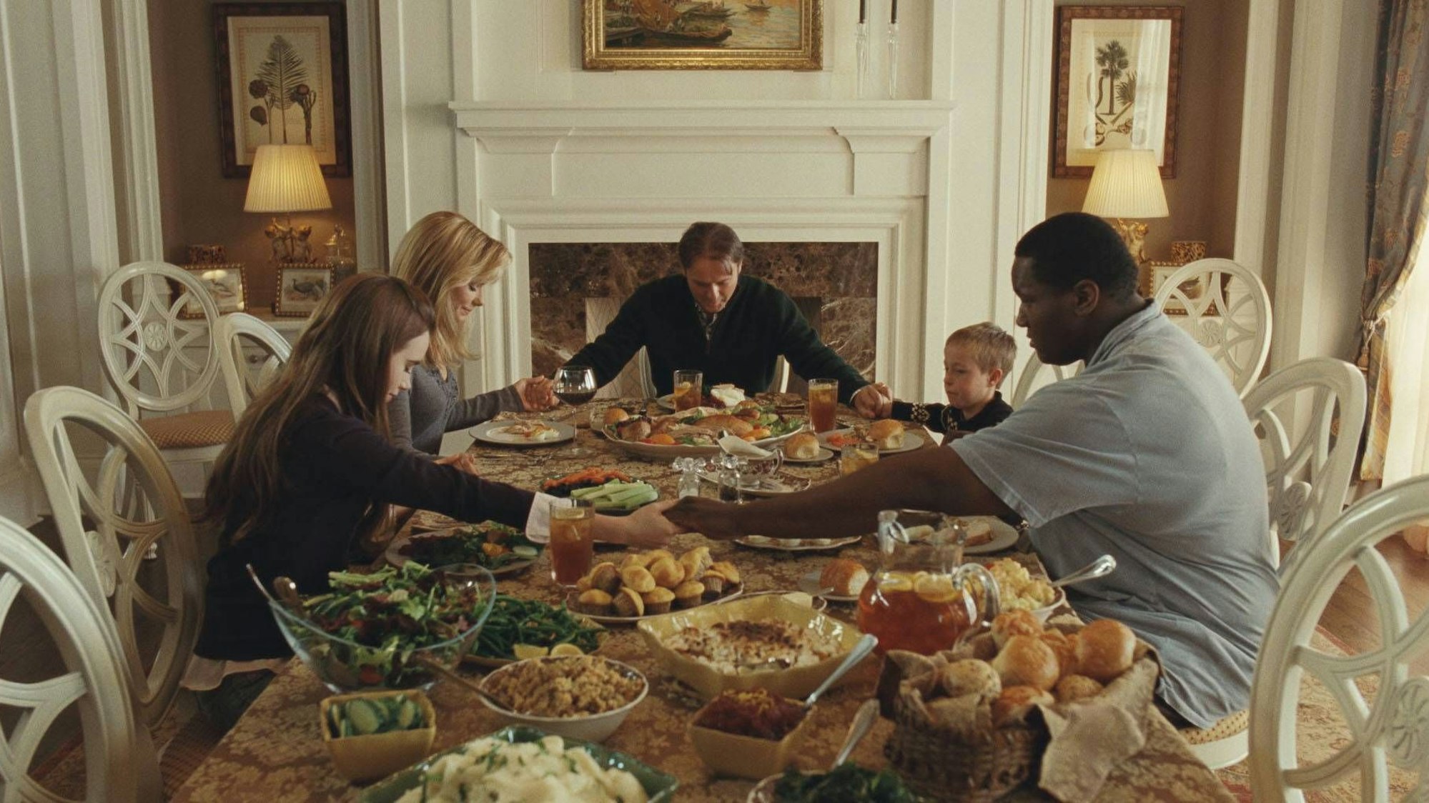 Szene aus dem Film „The Blind Side“: Der Blockbuster erzählt die Geschichte von Football-Star Michael Oher (gespielt von Quinton Aaron), hier gemeinsam beim Essen mit seinen vermeintlichen Adoptiveltern, Leigh Anne Tuohy (Sandra Bullock) und Sean Tuohy (Tim McGraw).